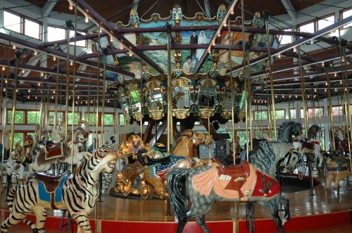 A colorful carousel featuring intricately designed horses and animals, set in a spacious indoor area.