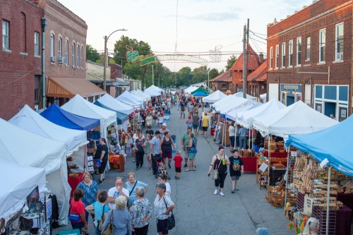 A bustling street market with numerous tents, vendors, and crowds of people enjoying the event.
