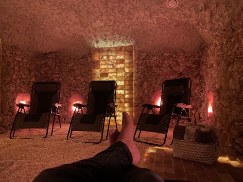 A serene salt room with stone walls, dim lighting, and reclining chairs for relaxation.