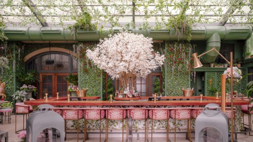 A vibrant bar area with a large white tree centerpiece, surrounded by greenery and floral decor.