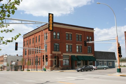 Historic brick building at a street corner, featuring traffic lights and a clear blue sky.