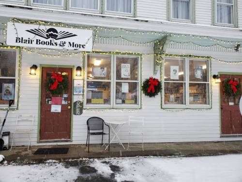 A cozy bookstore with festive decorations, wreaths, and lights, set in a snowy environment.