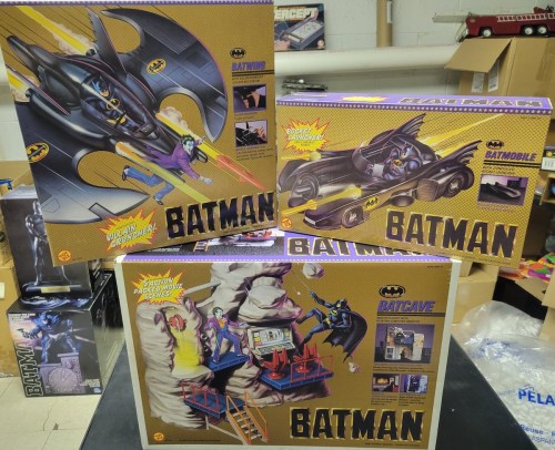 Three vintage Batman toy boxes featuring the Batmobile, Batcave, and a rocket launcher, all with colorful designs.