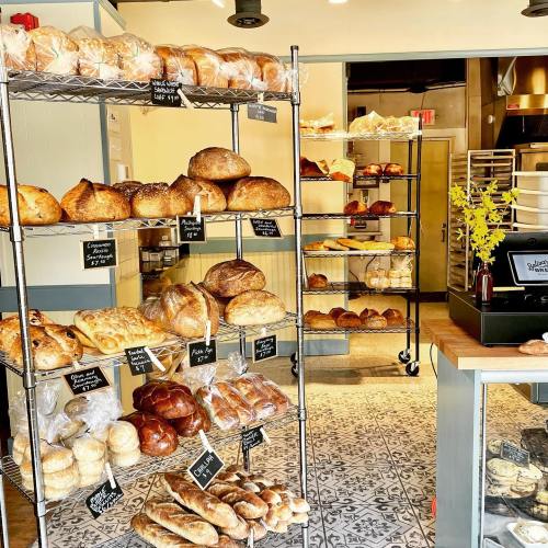 A bakery display featuring various types of bread on metal shelves, with a warm, inviting atmosphere.