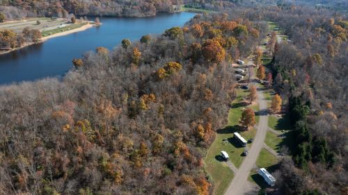 Aerial view of a river surrounded by autumn trees and a campground with several trailers along a winding road.