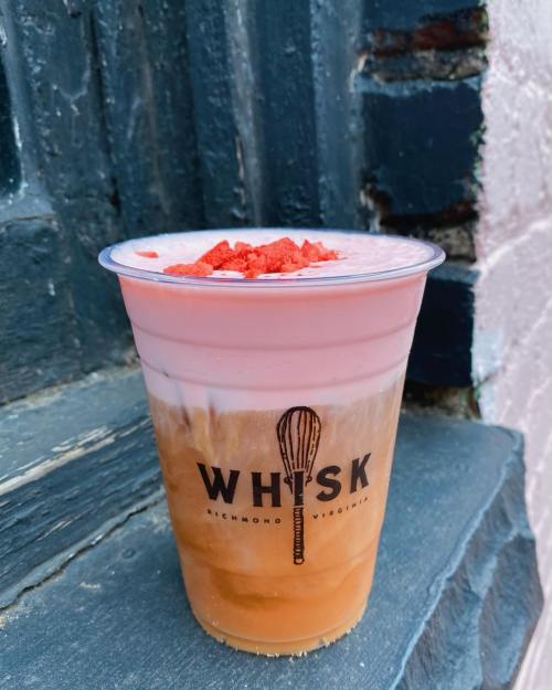 A layered drink in a clear cup topped with crushed strawberries, featuring the logo "WHISK" from Richmond, Virginia.