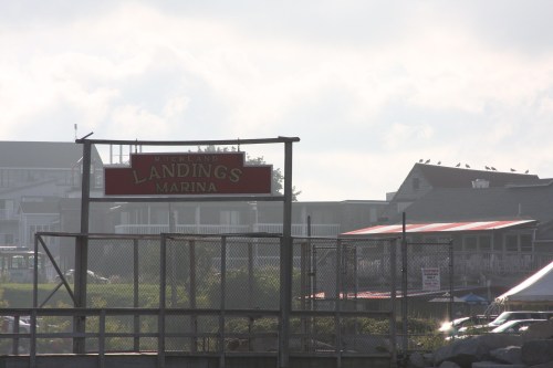 Sign for Rockland's Marina with buildings and a cloudy sky in the background.