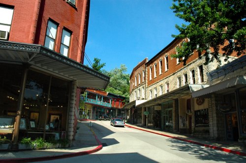 A charming street scene with historic buildings, shops, and a clear blue sky in a small town.