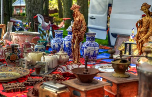 A vibrant outdoor market display featuring various antiques, including vases, figurines, and vintage kitchen items.