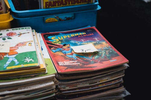 A stack of vintage comic books, featuring a Superman album on top, with a price tag of 3.
