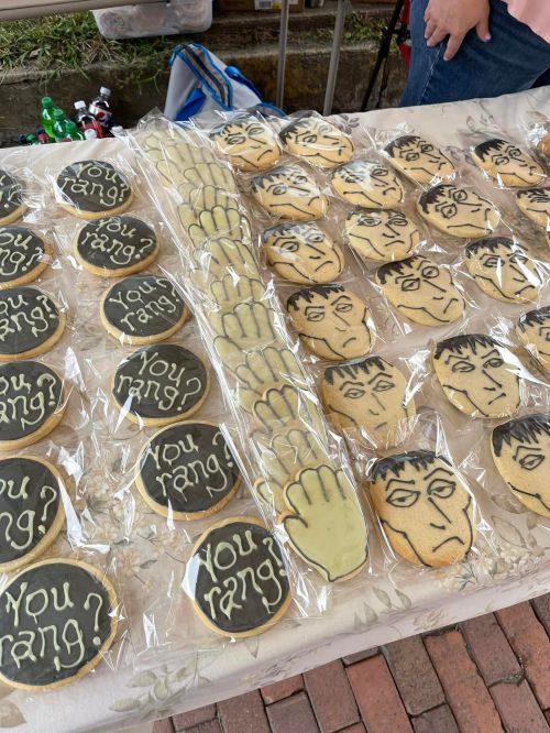 A table of decorated cookies featuring faces and the phrase "You rang?" in black icing on a light background.