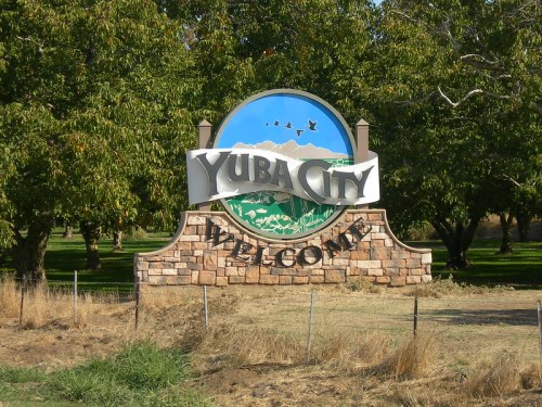 Welcome sign for Yuba City, featuring a colorful design and surrounded by trees and grass.