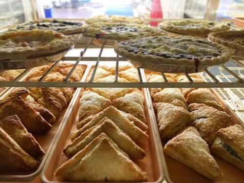 A display of freshly baked pies and pastries, including triangular pastries and various fruit pies.