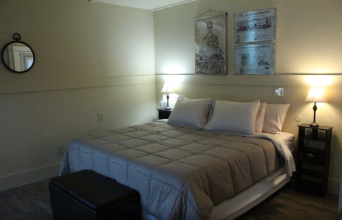 Cozy bedroom with a queen bed, bedside lamps, and decorative wall art in soft, neutral tones.
