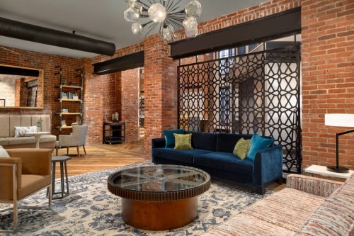 Cozy living area with exposed brick walls, stylish furniture, and a decorative glass coffee table.
