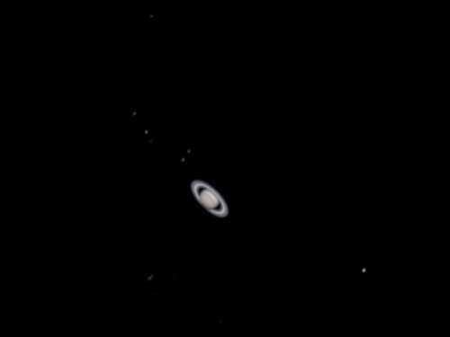 A detailed view of Saturn with its iconic rings, surrounded by several small moons against a black background.