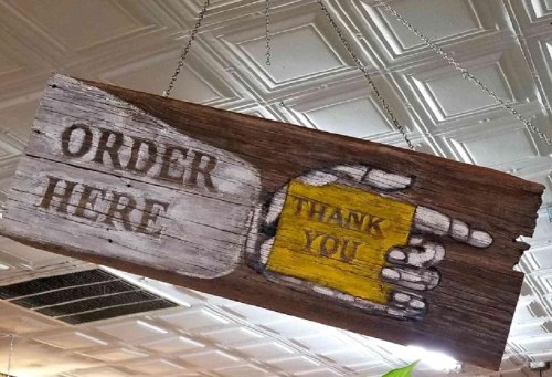 Wooden sign with painted text: "ORDER HERE" on one side and "THANK YOU" with a pointing hand on the other.