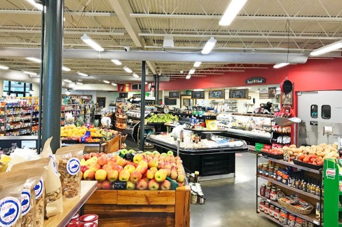 A vibrant grocery store interior filled with fresh produce, snacks, and various food items on display.