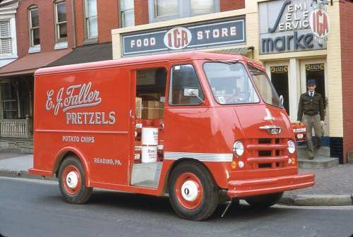 A vintage red delivery truck with "E.F. Tuller Pretzels" and "Potato Chips" signage parked in front of a store.