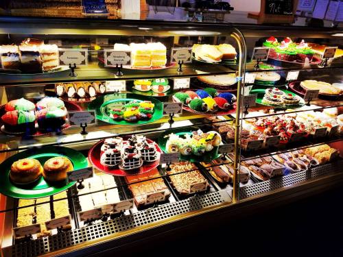 A display case filled with a variety of colorful cakes, pastries, and desserts, each labeled with names.