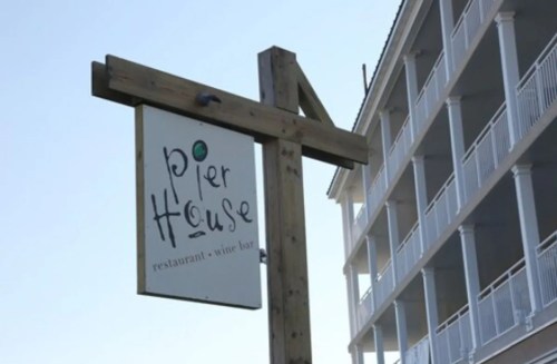 Sign for "Pier House" restaurant and wine bar, with a building in the background.