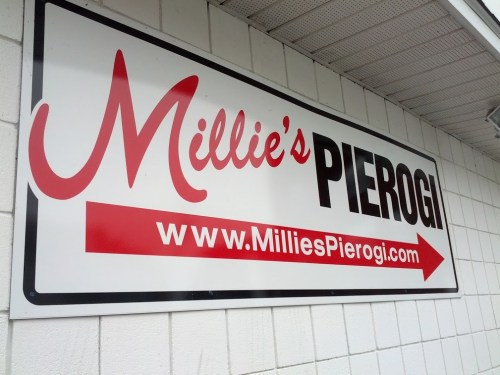 Sign for Millie's Pierogi with website URL and an arrow pointing to the right.