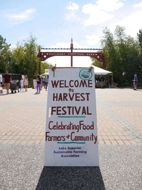 A sign welcoming visitors to the Harvest Festival, celebrating food, farmers, and community at Bayfront Festival Park.