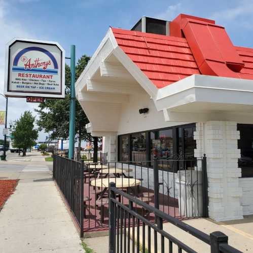 Exterior of Anthony's Restaurant featuring a red and white roof, outdoor seating, and an "Open" sign.