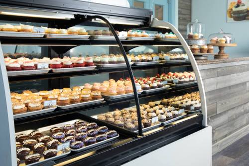 A display case filled with a variety of colorful cupcakes and desserts in a bakery setting.