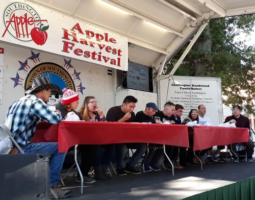 A group of participants seated at a table during the Apple Harvest Festival, with banners and decorations in the background.