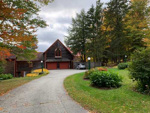 A scenic view of a house with a driveway, surrounded by trees and colorful autumn foliage.