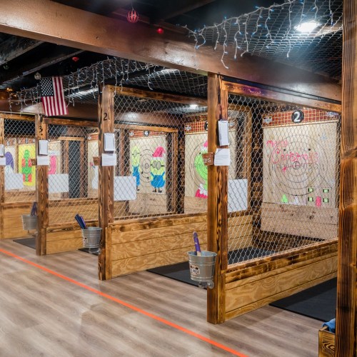 A brightly lit indoor facility with wooden booths for games, decorated with colorful drawings and string lights.