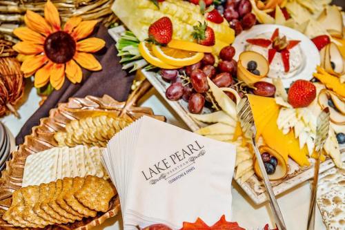 A colorful spread of fruits, cheeses, and crackers, with a decorative sunflower and napkins featuring "Lake Pearl."