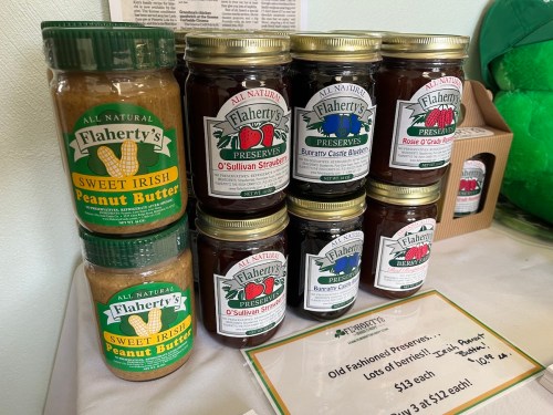 Jars of Flaherty's all-natural preserves and peanut butter displayed on a table with a price sign.