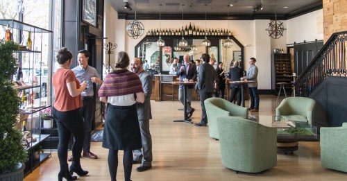A lively gathering in a stylish venue with people socializing and enjoying drinks in a modern setting.