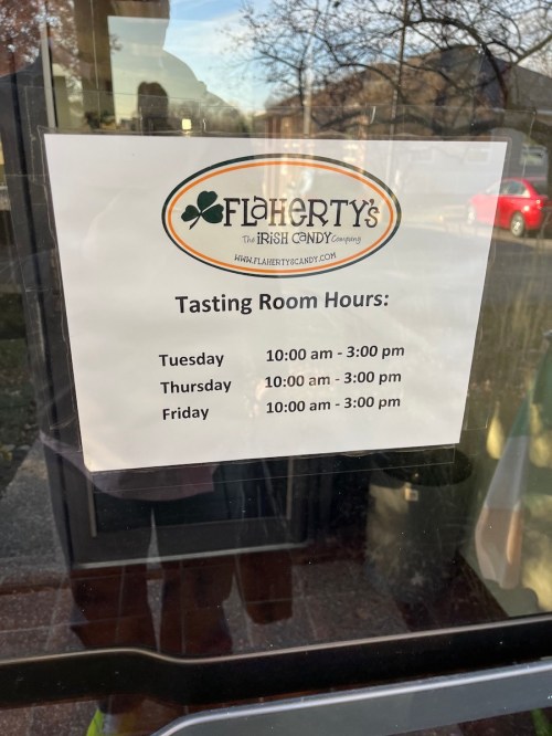 Sign on a door displaying Flaherty's Irish Candy tasting room hours for Tuesday, Thursday, and Friday.