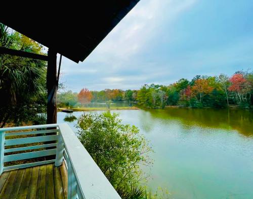 A serene view of a lake surrounded by trees with autumn foliage, seen from a wooden deck.