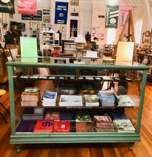 A display case filled with books and pamphlets in a vintage shop, surrounded by various antique items.