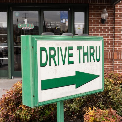 Sign directing customers to the drive-thru, with an arrow pointing right, in front of a restaurant.