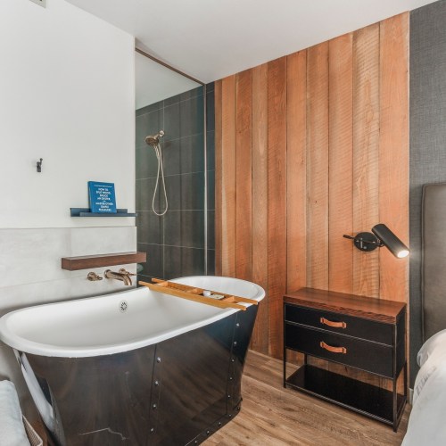 A modern bathroom featuring a black freestanding bathtub, wooden accents, and a sleek shower area.