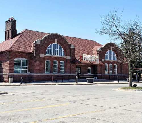 Historic brick building with arched windows and a sloped roof, set against a clear blue sky.