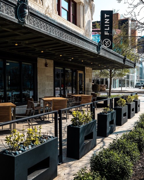 Outdoor seating area of a restaurant named "Flint," featuring planters and a stylish facade.