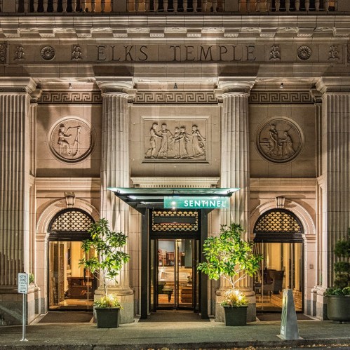 Entrance of the Elks Temple, featuring ornate architecture and illuminated signage for the Sentinel hotel.