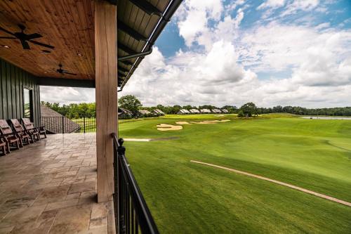 View from a porch overlooking a lush green golf course under a partly cloudy sky.