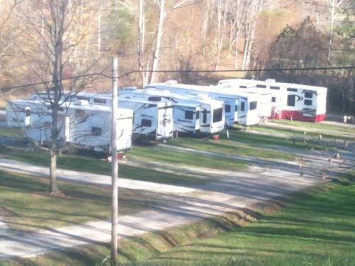 A row of parked RVs on a gravel path, surrounded by trees and grass in a rural setting.