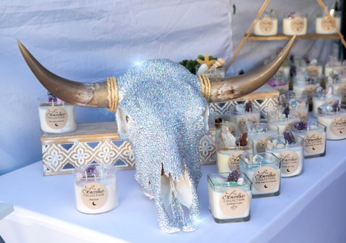 A sparkling rhinestone-covered bull skull displayed among decorative candles on a table.