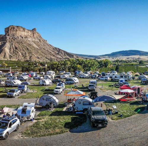 A scenic campsite with various RVs and tents set against a backdrop of mountains and clear blue skies.
