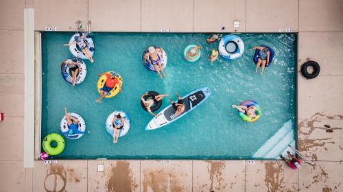 Aerial view of a pool filled with people on inflatable floats, enjoying a sunny day.