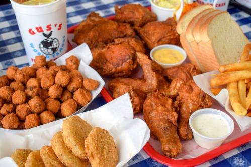 A vibrant spread of fried chicken, okra, fries, bread, and dipping sauces on a checkered tablecloth.