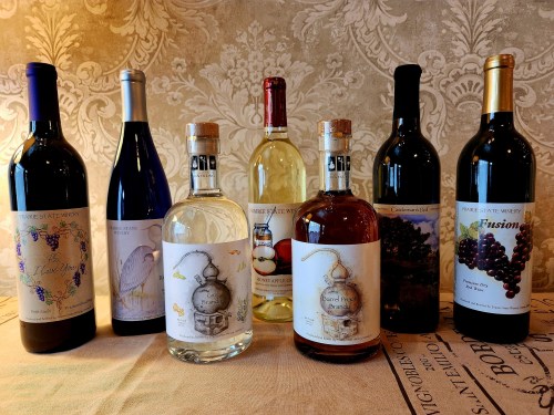 A collection of eight wine bottles with various labels, displayed on a textured tablecloth against a decorative background.